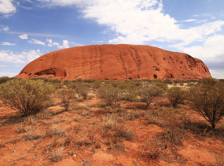 Uluru in the distance against a blue sky
