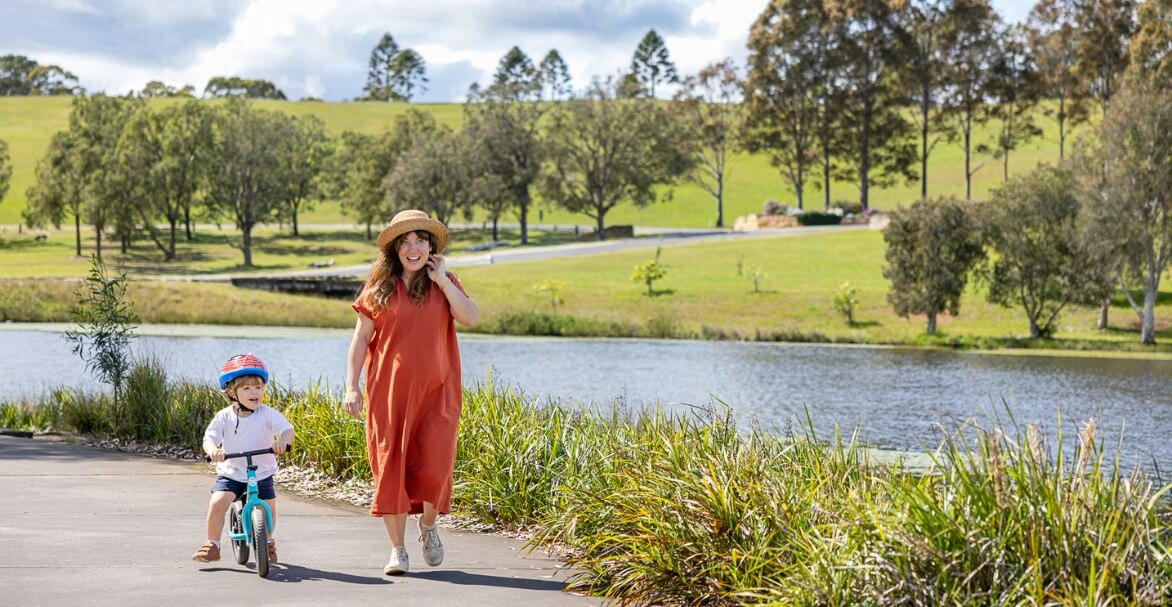 mum with toddler on bike next to lake