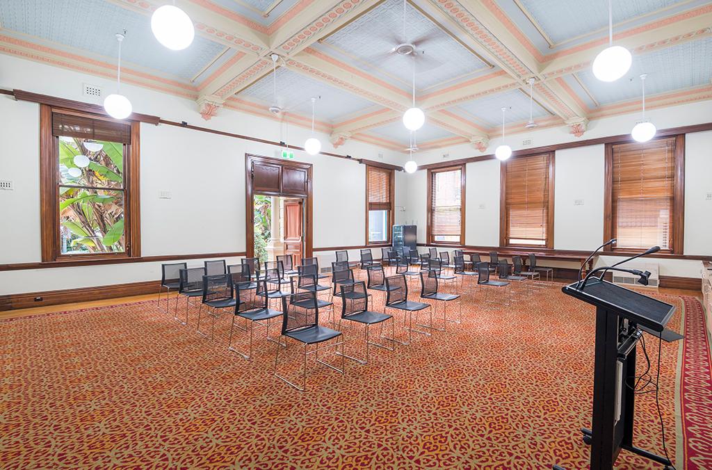 Lectern and chairs in a grand room with elaborate Victorian-era ceiling
